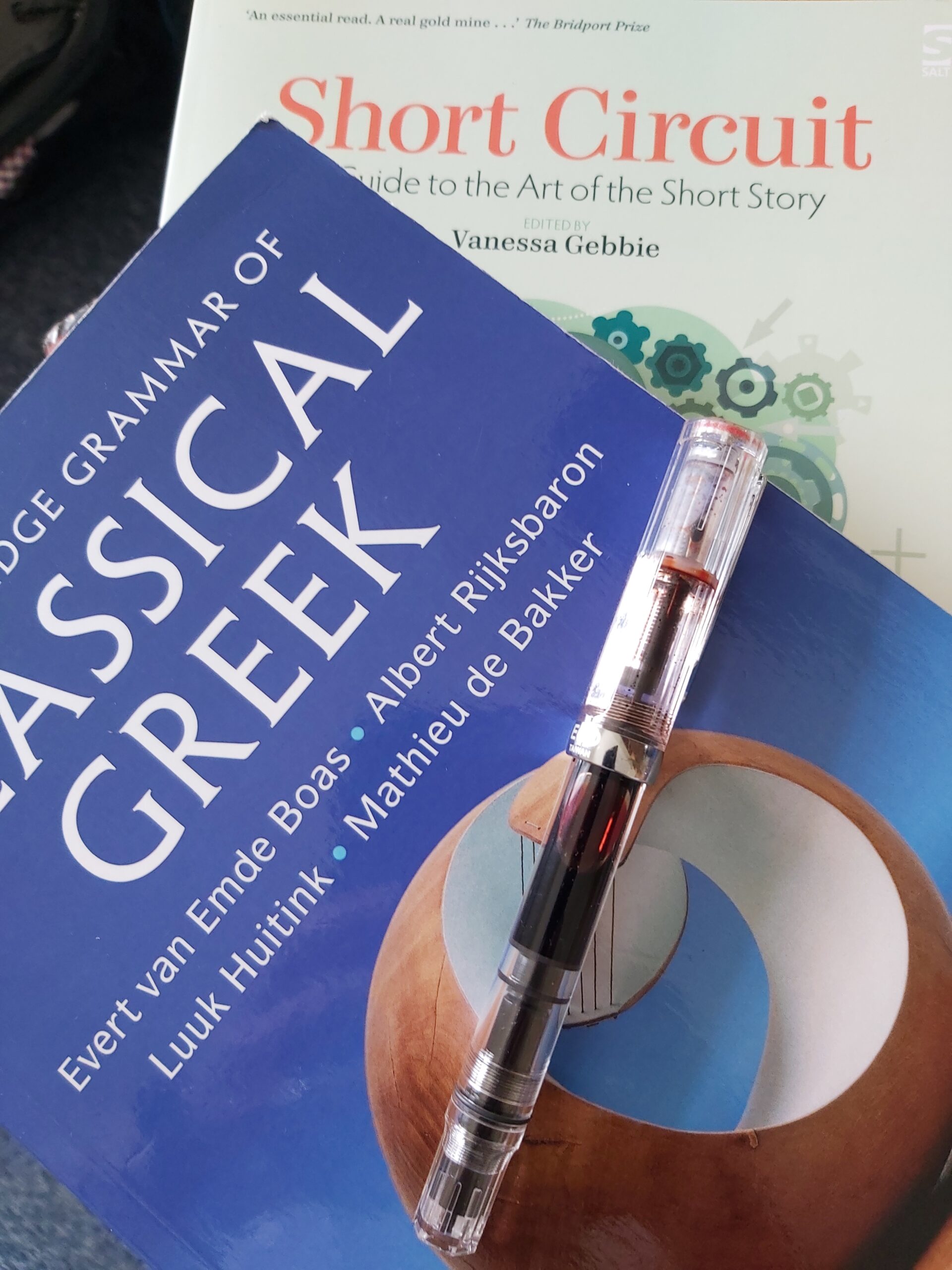 Image shows an ancient Greek grammar and a guide to short story writing with a fountain pen on top